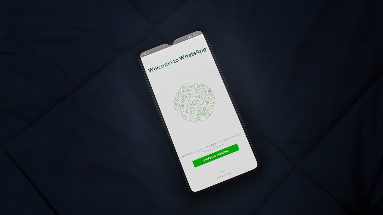 Smartphone displaying WhatsApp login screen on a dark surface. Overhead view.